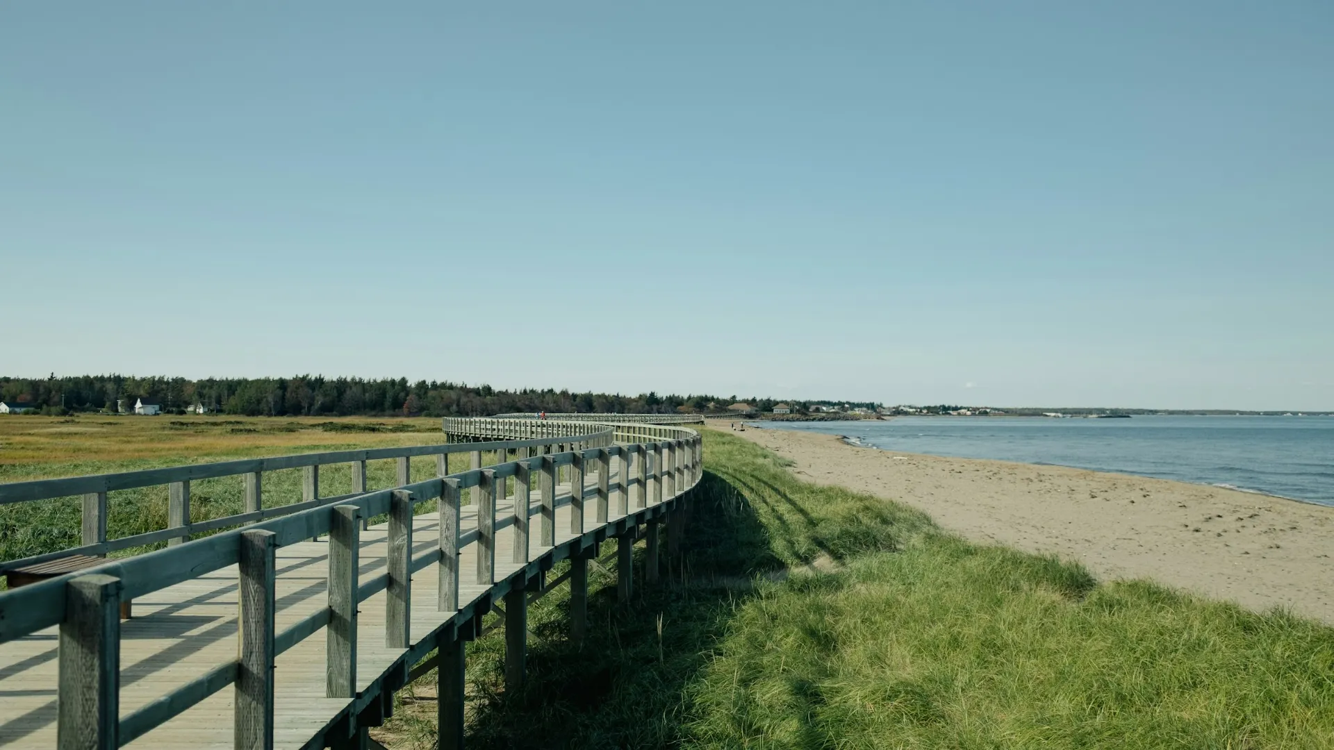 Une promenade de bois qui longe une plage de sable